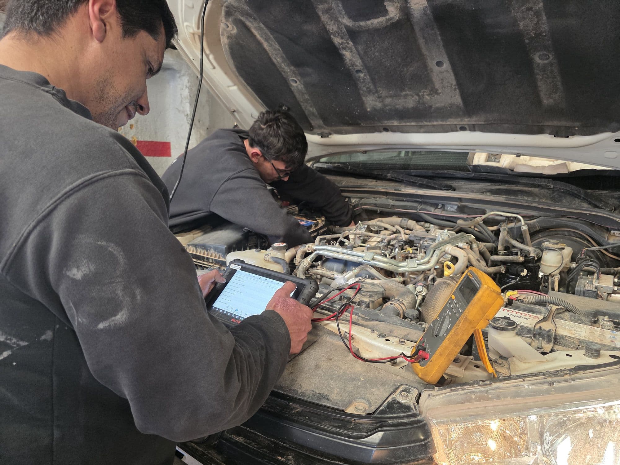 Dos técnicos revisando el motor con equipo de diagnóstico